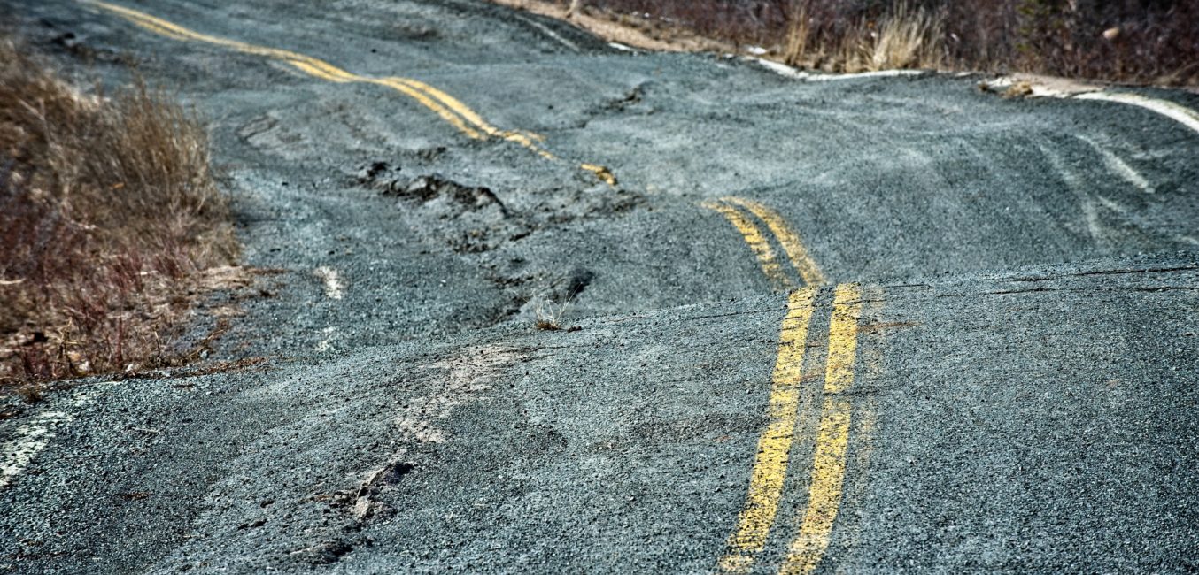 Permafrost damage to a road in the Canadian arctic.  Buckled pavement and copy space.